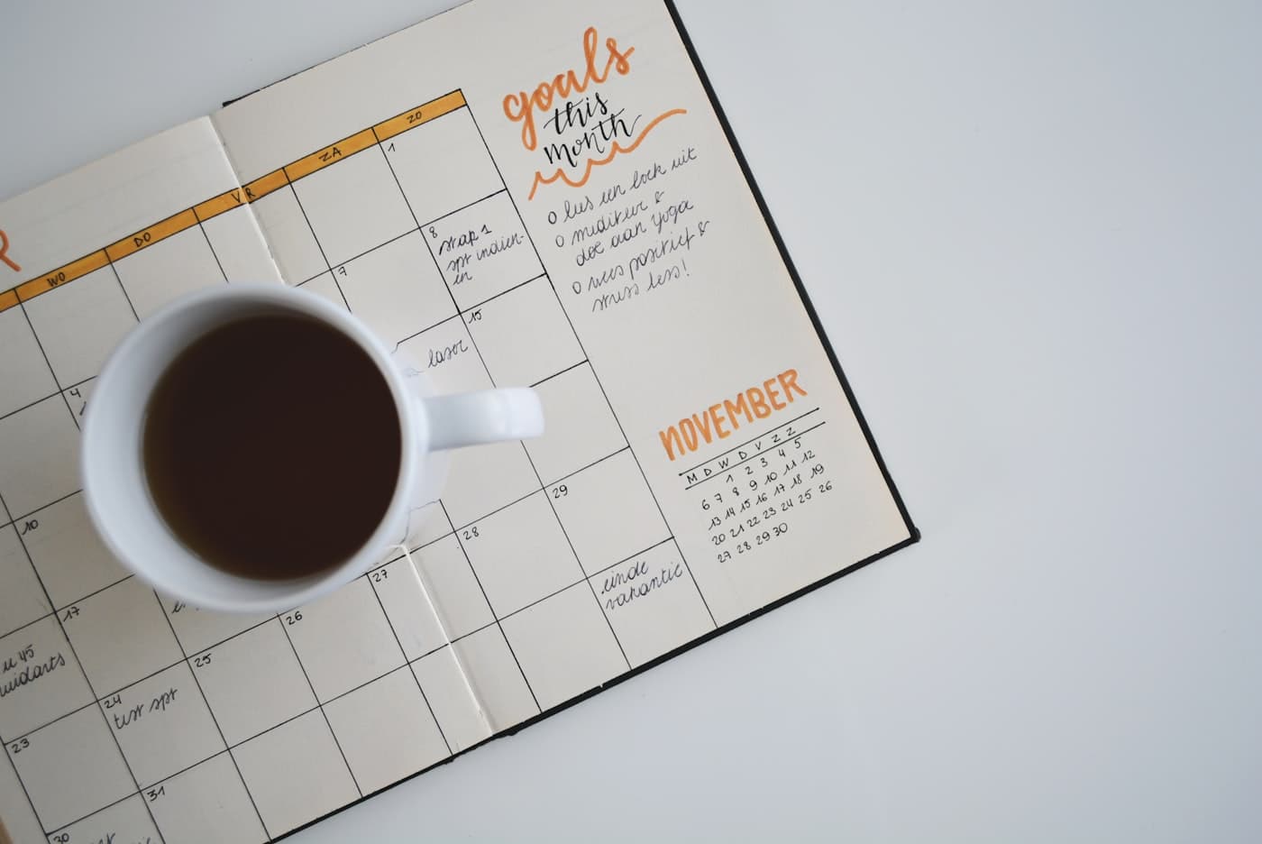 Aufgeschlagener Monatskalender mit einer Tasse Kaffee
